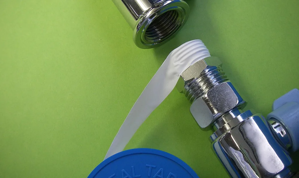 a white thread seal tape is wrapped on a faucet made of stainless steel