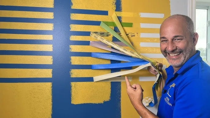 a painter peeling of painter's tape to creat patterns on the wall