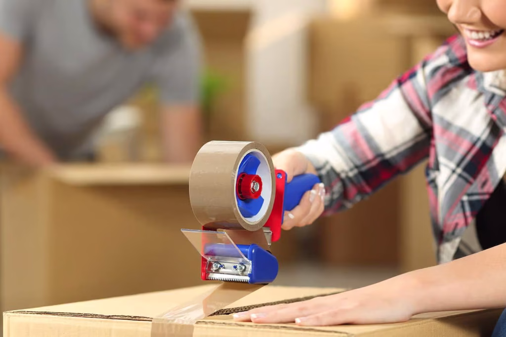 a woman using a dispensor to pack a box