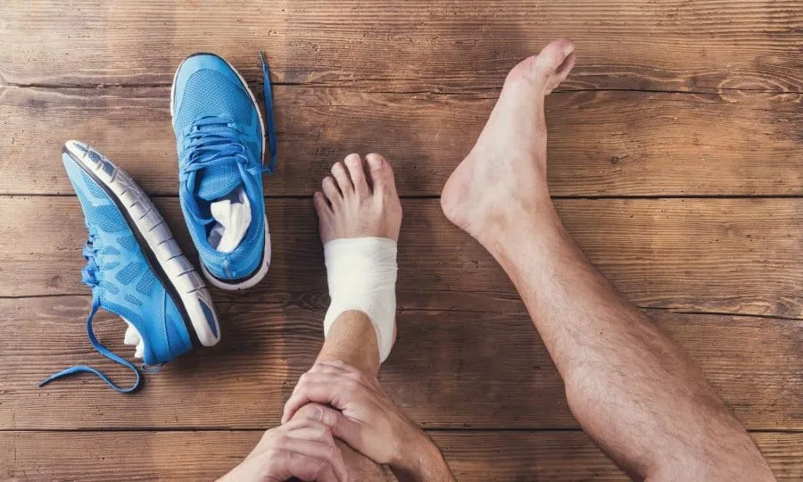 an athletes is applying zinc oxide tape on ankel